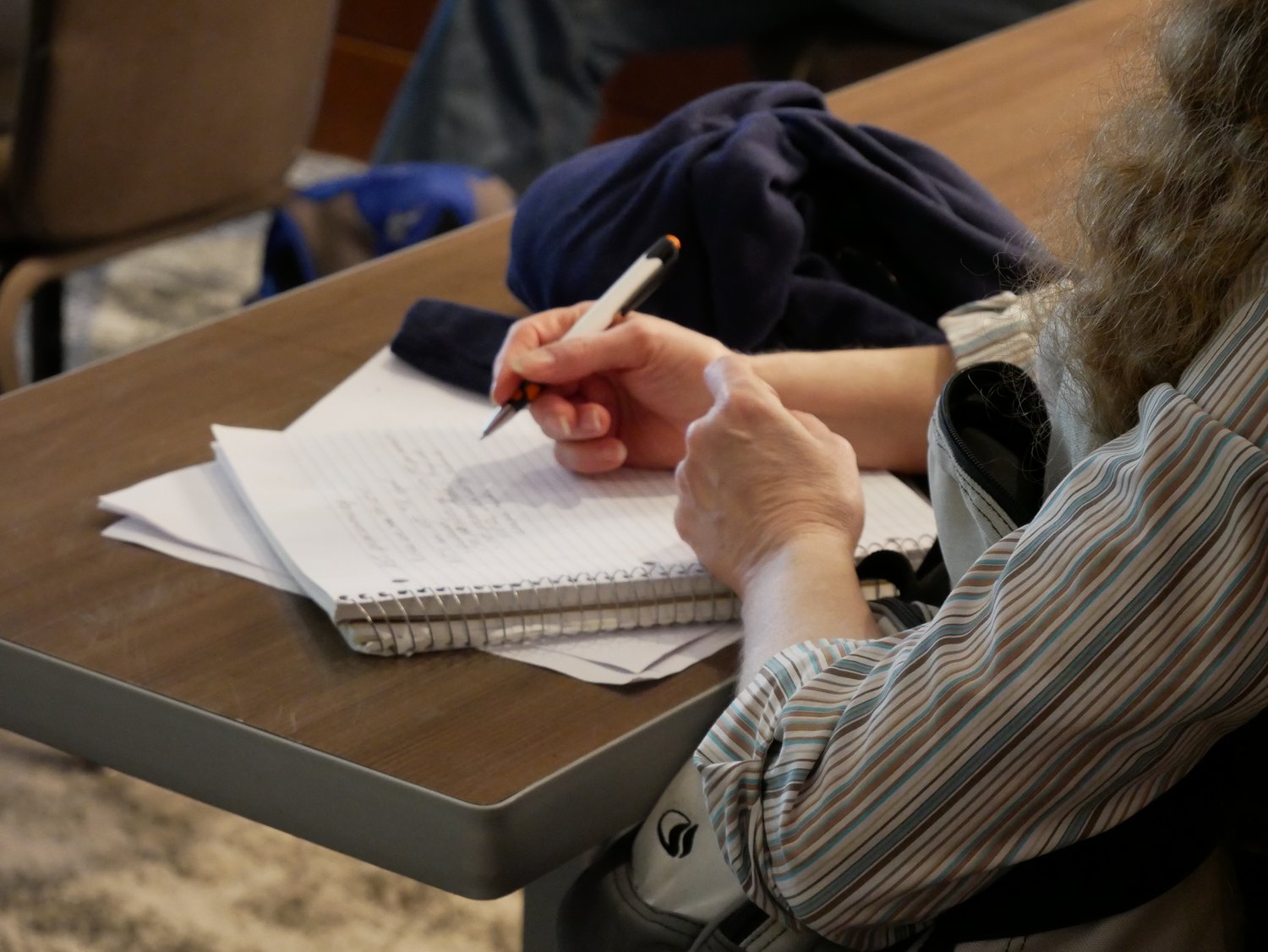 Woman writing on notepad on classroom table